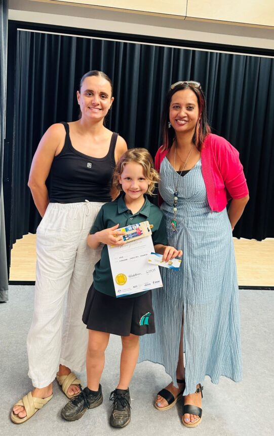 student holding award prize with teachers standing beside them