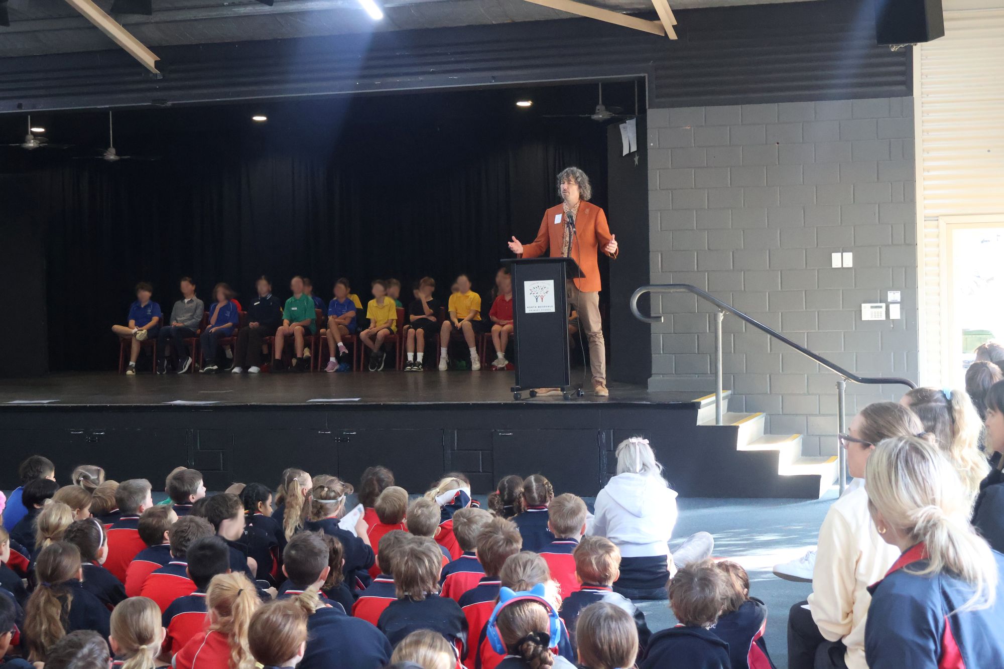 Frank Mitchell on stage speaking to primary school students