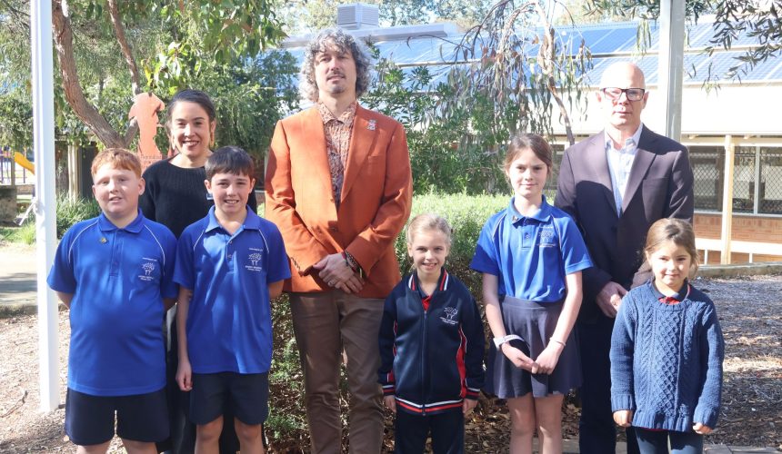 Adults and primary school students standing and smiling